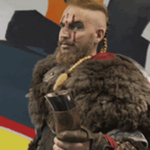 a man with a beard and a fur coat is holding a sword .
