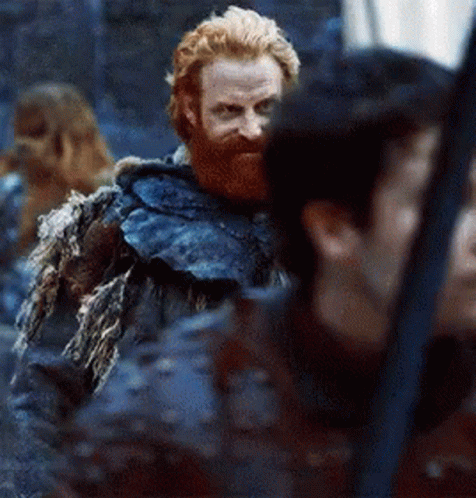 A Man With A Beard And A Fur Coat Is Standing Next To A Woman . GIF
