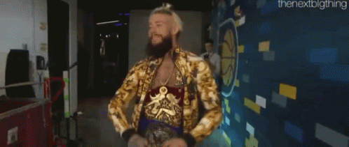 a man with a beard and a gold jacket is standing in front of a wall .