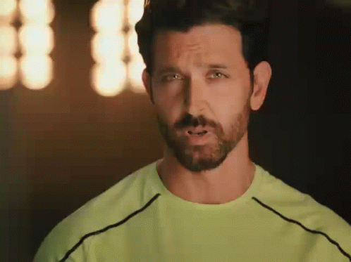 A Man With A Beard And A Green Shirt Is Making A Face . GIF