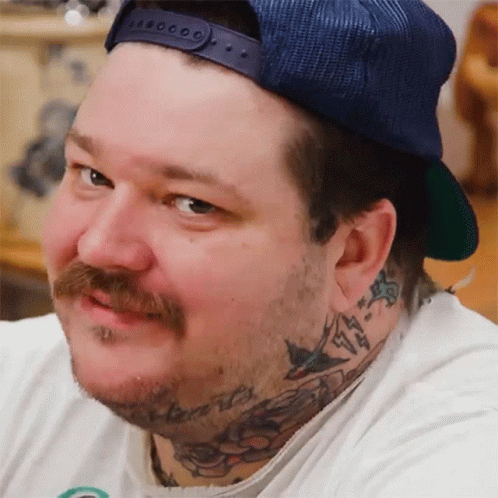 A Man With A Beard And A Hat Has A Tattoo On His Neck GIF