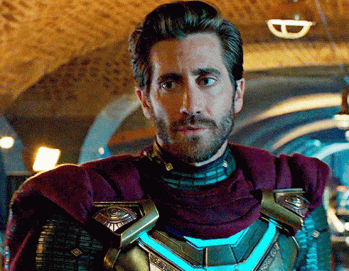 A Man With A Beard And A Purple Cape Is Standing In A Dark Room GIF