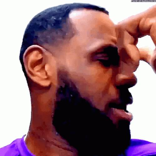 A Man With A Beard And A Purple Shirt Scratching His Nose GIF
