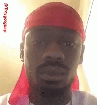 A Man With A Beard And A Red Headband Is Making A Funny Face . GIF
