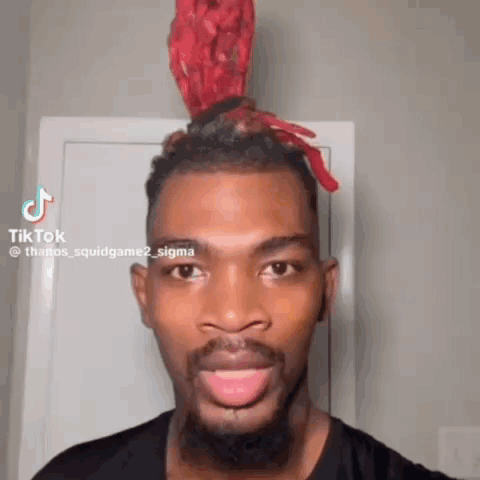 A Man With A Beard And A Red Headband On His Head Is Smiling And Looking At The Camera . GIF