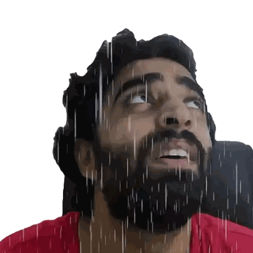 a man with a beard and a red shirt is looking up at the rain