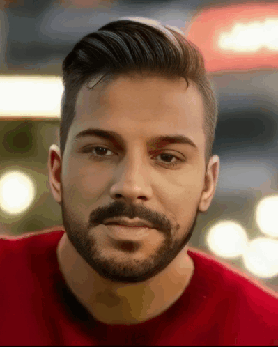 A Man With A Beard And A Red Shirt Looks At The Camera GIF