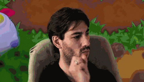 A Man With A Beard And A Ring On His Finger Is Sitting In A Chair GIF