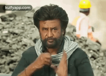 A Man With A Beard And A Scarf Around His Neck Is Holding A Roll Of Wire . GIF
