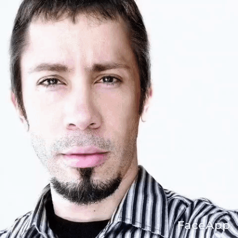 A Man With A Beard And A Striped Shirt Is Making A Funny Face . GIF
