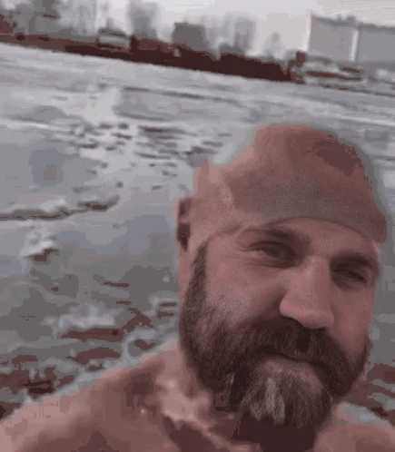 A Man With A Beard And A Swim Cap Is Swimming In The Water GIF