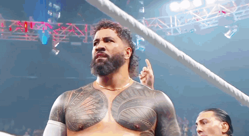 a man with a beard and a tattoo on his chest is standing in a ring .