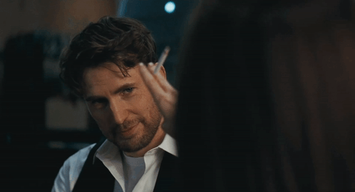 a man with a beard and a white shirt is looking at a woman