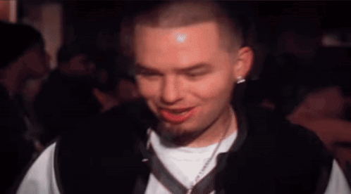 A Man With A Beard And A White Shirt Is Making A Funny Face . GIF