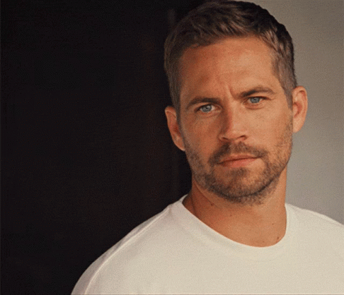 A Man With A Beard And A White Shirt Looks At The Camera GIF