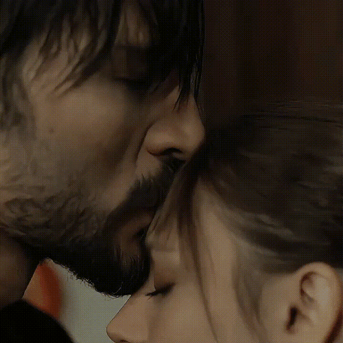 A Man With A Beard And A Woman With Long Hair Are Touching Their Noses GIF