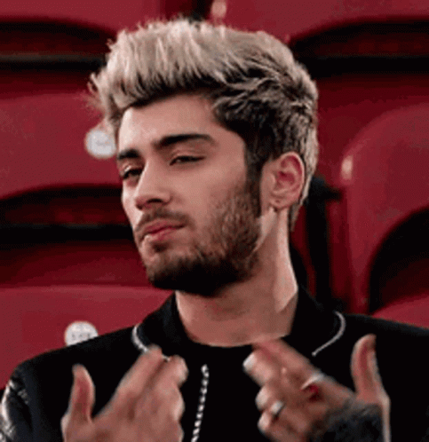 A Man With A Beard And Blonde Hair Is Sitting In A Stadium With Red Seats . GIF