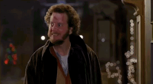 A Man With A Beard And Curly Hair Is Standing In Front Of A Doorway . GIF