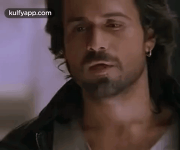 A Man With A Beard And Earrings Is Wearing A Leather Jacket . GIF