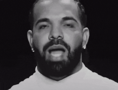 A Man With A Beard And Earrings Looks At The Camera GIF