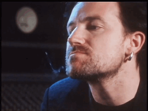 a man with a beard and earrings looks at the camera