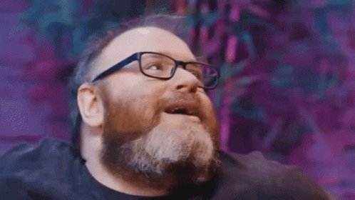 A Man With A Beard And Glasses Is Looking Up And Smiling . GIF