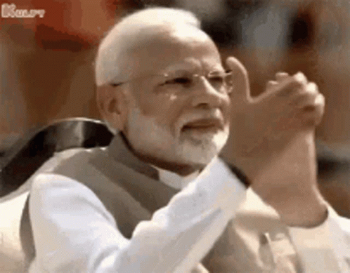 A Man With A Beard And Glasses Is Sitting In A Chair With His Hands In The Air . GIF