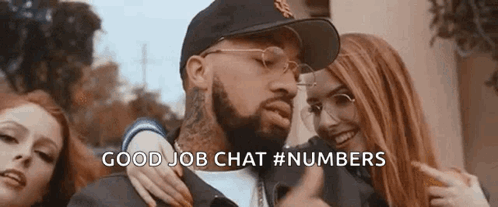 A Man With A Beard And Glasses Is Standing Next To Two Women And Pointing At Them . GIF