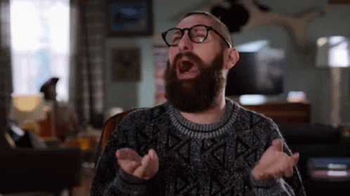 Man With Beard And Glasses Yawning In Living Room GIF