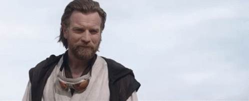 A Man With A Beard And Goggles Is Standing In Front Of A Cloudy Sky And Saying `` Hello There '' . GIF