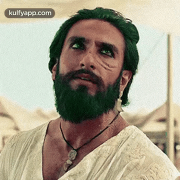 A Man With A Beard And Green Hair Is Wearing A Necklace And A White Shirt . GIF
