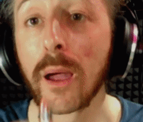 A Man With A Beard And Headphones Is Applying Lipstick To His Lips GIF