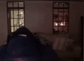 A Man With A Beard And Headphones Is Standing In Front Of A Window . GIF