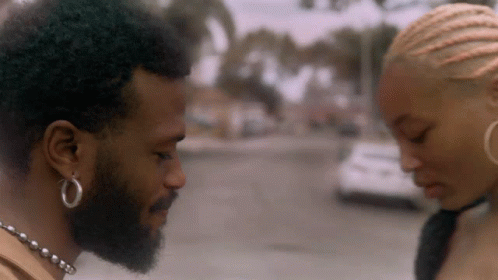 A Man With A Beard And Hoop Earrings Is Looking At A Woman GIF