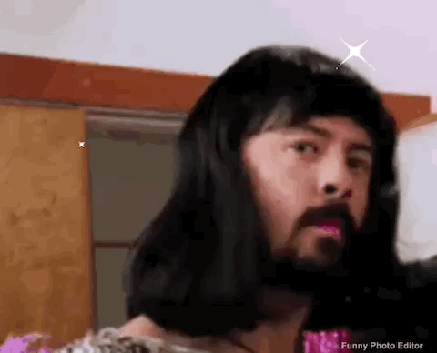 A Man With A Beard And Long Hair Is Wearing A Wig And Making A Funny Face . GIF