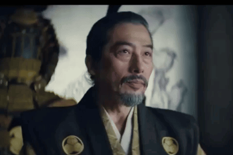 a man with a beard and mohawk is wearing a samurai costume and looking at the camera .