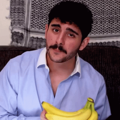 A Man With A Beard And Mustache Is Holding A Bunch Of Bananas GIF