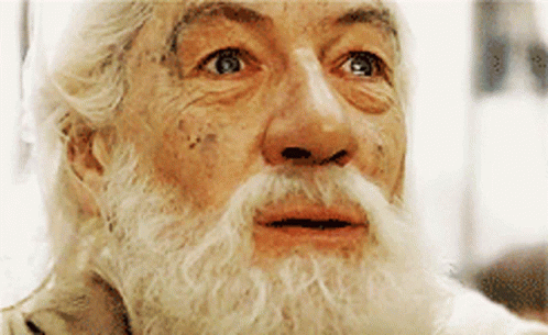A Man With A Beard And Mustache Is Looking At Something GIF