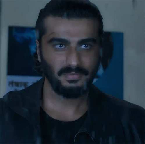 A Man With A Beard And Mustache Is Looking At The Camera In Front Of A Sign That Says ' A ' On It GIF