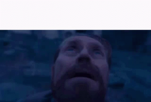 A Man With A Beard And Mustache Is Looking Up At The Sky In A Dark Room . GIF