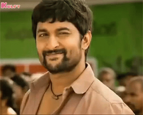 A Man With A Beard And Mustache Is Smiling And Looking At The Camera . GIF