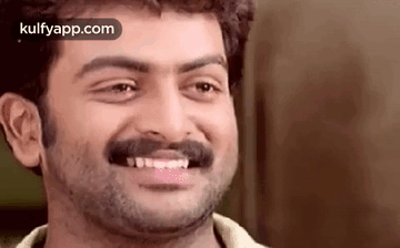 A Man With A Beard And Mustache Is Smiling And Looking At The Camera . GIF