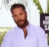a man with a beard and mustache is standing in front of a sign that says `` de hon sa '' .