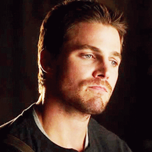 A Man With A Beard And Mustache Is Wearing A Black Shirt And Looking At The Camera . GIF
