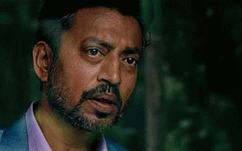A Man With A Beard And Mustache Is Wearing A Blue Suit And A Purple Shirt . GIF