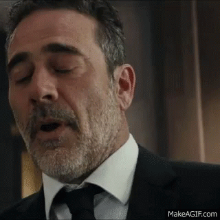 A Man With A Beard And Mustache Is Wearing A Suit And Tie And Yawning . GIF