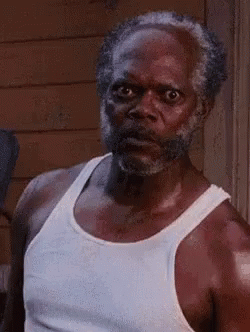 A Man With A Beard And Mustache Is Wearing A White Tank Top . GIF