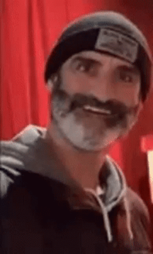 A Man With A Beard And Mustache Wearing A Beanie And A Hoodie . GIF