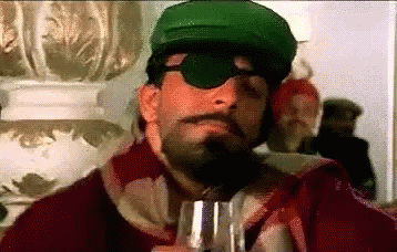 A Man With A Beard And Mustache Wearing A Green Hat And Sunglasses Is Holding A Glass Of Wine . GIF