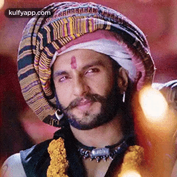 A Man With A Beard And Mustache Wearing A Turban And A Necklace . GIF